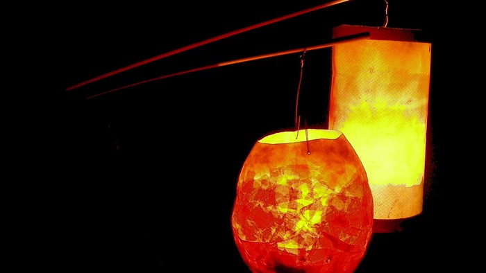 Zwei beleuchtete Laternen hängen an einem Balken