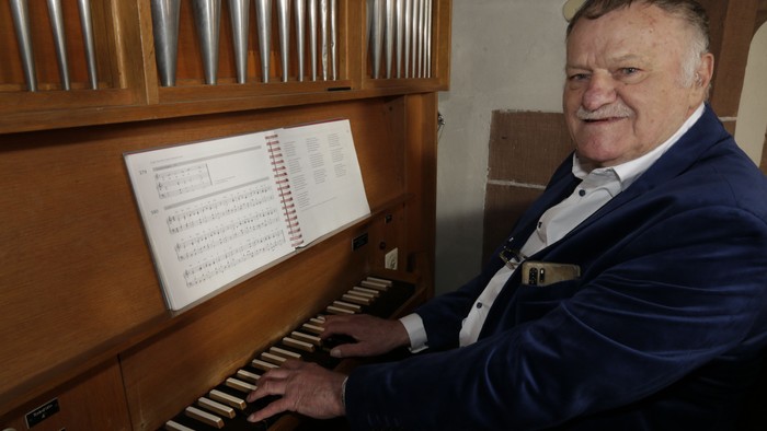 Mann im Anzug und mit Krawatte, der Orgel spielt