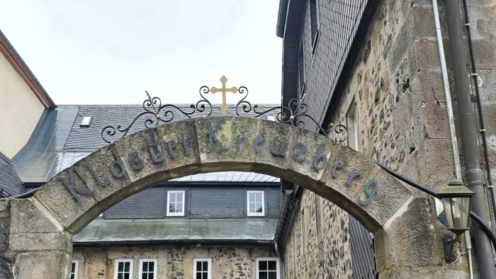 Steinbogen mit Kreuz über altem Gebäude