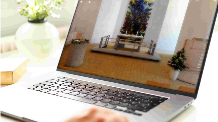 En person bruger en laptop til at se indendørs billeder af en julestue med julerødder og pynt.