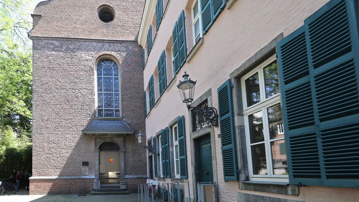 Das Bild zeigt einen historical Gebäude mit einem Glockenturm und grünen Fensterläden.