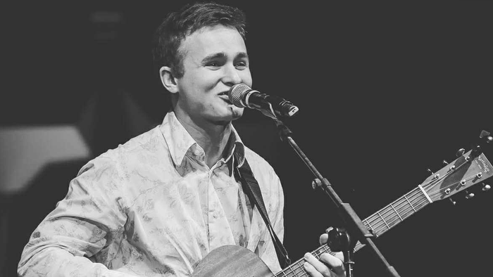 Mand, der synger og spiller guitar på scenen.