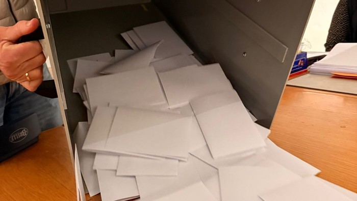 Person, die einen grauen Aktenschrank leert, während Papiere herausfallen.