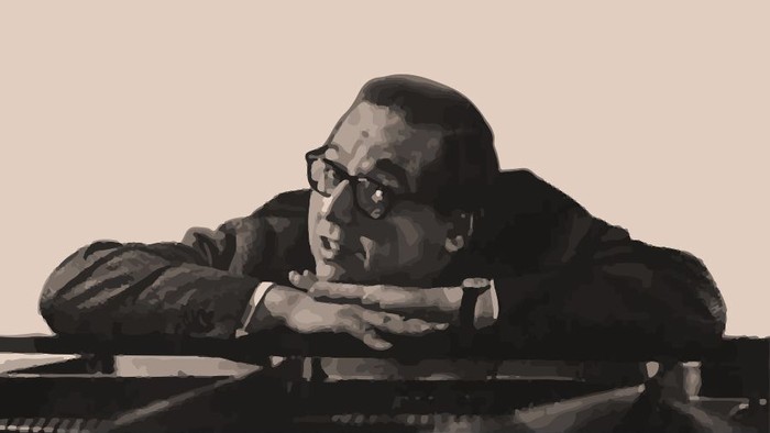 Georg Kreisler lehnt auf seinen Armen auf einem Klavier