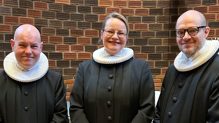 Tre præster står sammen i kirke.