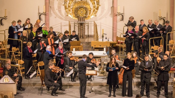 Ein Orchester probt in einer Kirche unter einem großen Kronleuchter