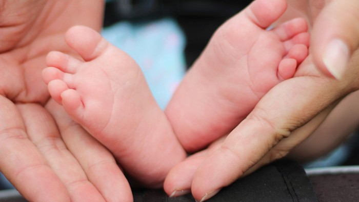 En person holder en spæd barnes føder.