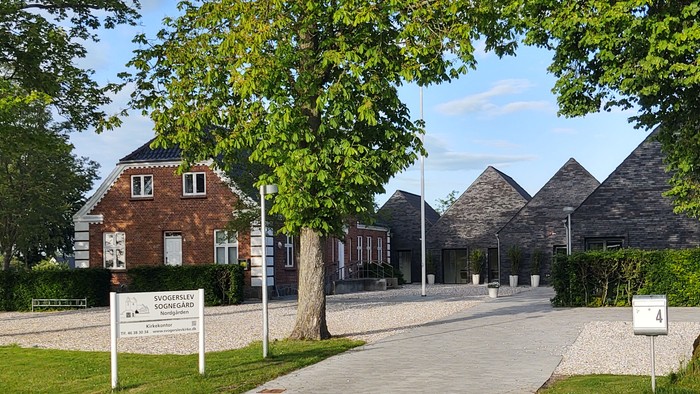 En smuk vej med træer og hus.