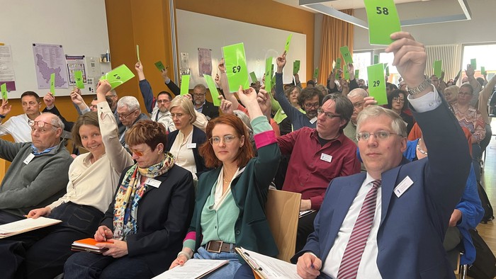 Foto von Synodalen bei der Abstimmung. Im Vordergrund u. a. Superintendent Christian Notmeier und seine Stellvertretenden