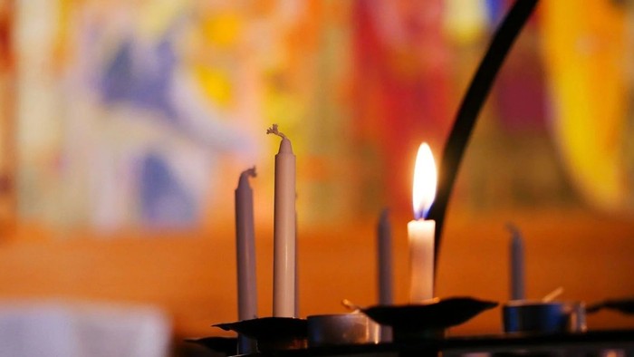 Lys tændt foran en farverig, sløret baggrund.