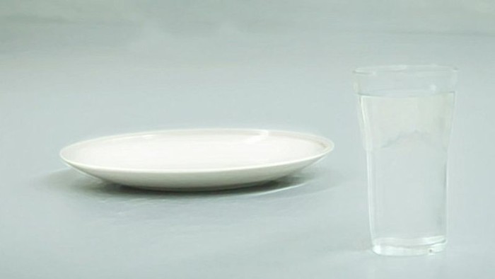 En blank plate og en glas med vand på en blå badebræt.