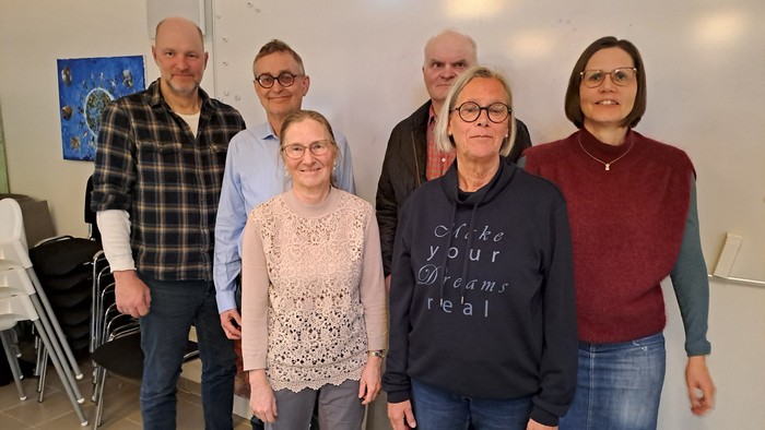 En gruppe af seks personer står sammen i et rum.