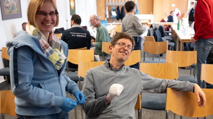 Zwei Personen halten Eistüten in einem Raum mit anderen Leuten.