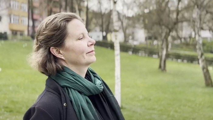 Frau im Park mit geschlossenen Augen und grüner Schals