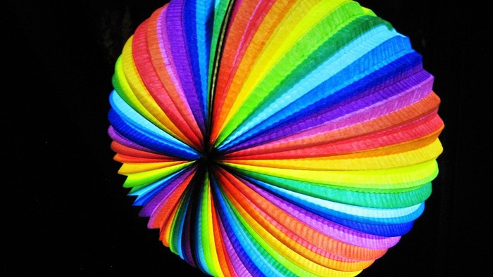 Bunter, gefalteter Papier-Laternen-Luftballon vor schwarzem Hintergrund