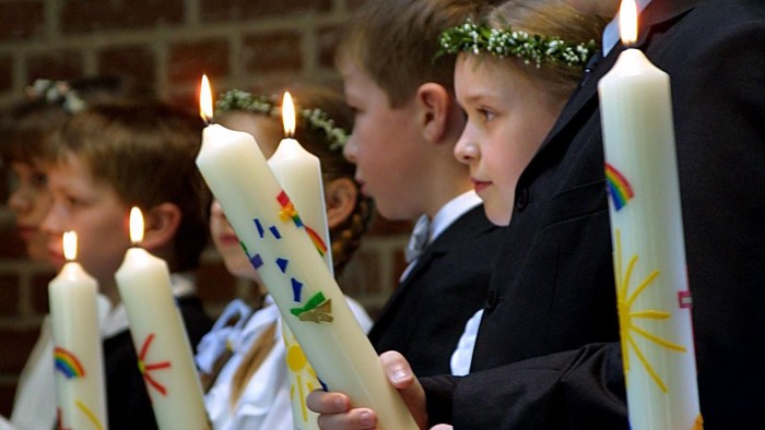 Kinder, die in einer Reihe brennende Kerzen halten