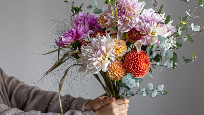 Eine Hand, die einen bunten Blumenstrauß hält.