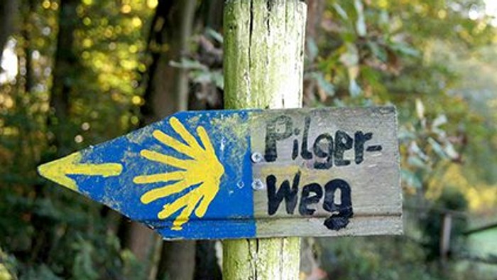 Holzschild mit gelber Muschel und der Aufschrift 
