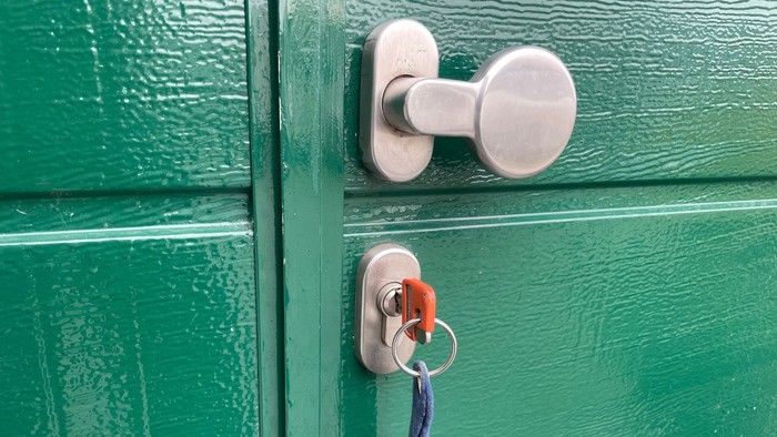 Grüne Tür mit silbernem Türknauf und eingestecktem Schlüssel.