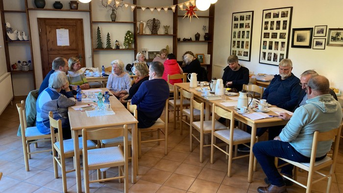Gruppe von Menschen, die in einem gemütlichen Restaurant an langen Tischen essen.