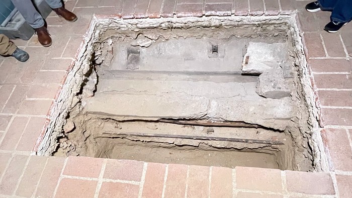 Menschen, die um ein großes Loch im Boden stehen.