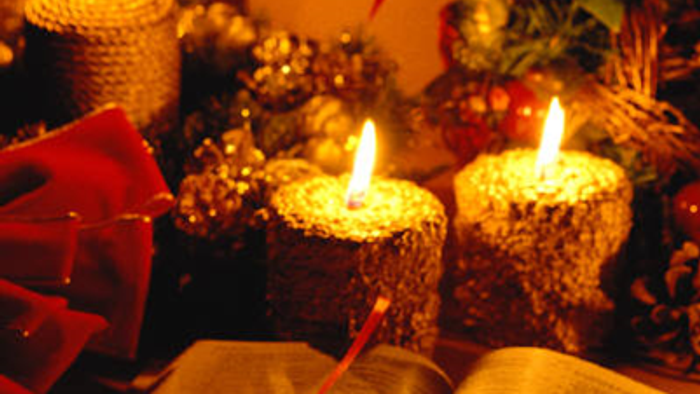 En åben bog med lysende lys og røde blomster