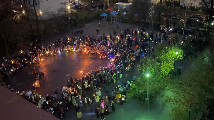 Ein großer Kreis von Menschen sammelt ich auf einem Schulhof am Abend und sieht eine Aufführung