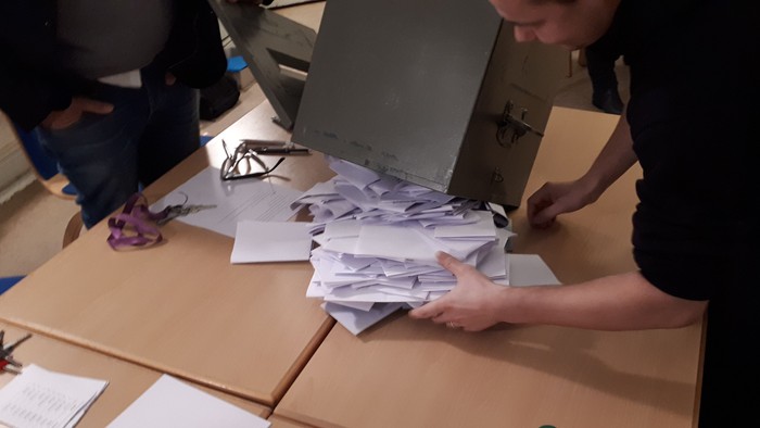 Eine Person sortiert Papiere auf einem Tisch mit Kartons.