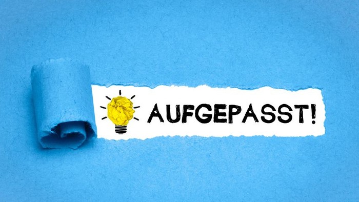 Zerrissenes Papier mit Glühbirne und deutschem Text „AUFGEPASST!“