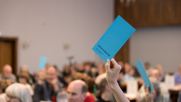 Menschen mit blauen Karten in einem Raum.
