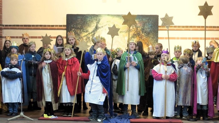 Eine Gruppe von Menschen in farbenfrohen Kostümen singt und spielt Musik in einer Kirche.