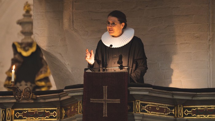 Ein Mann in priesterlicher Kleidung predigt an einem Pult in einer Kirche.