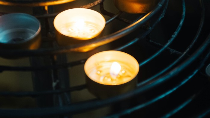 Several lit candles in a circular holder.