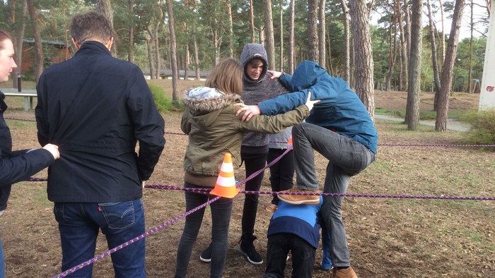 Eine Gruppe von Menschen spielt im Park ein Spiel mit einer Schnur.