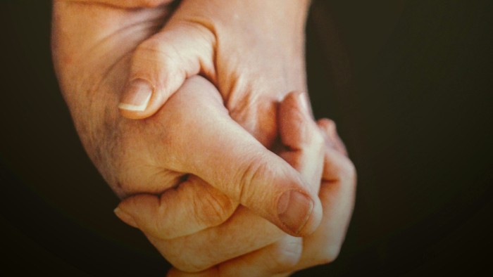 Eine ältere Person, die die Hand eines Kindes hält.