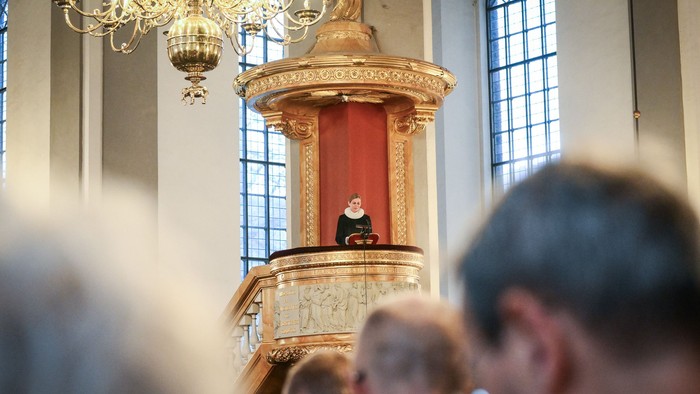 Mennesker i kirken, præst ved prædikestolen.