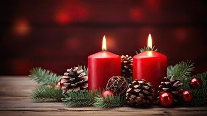 Zwei brennende rote Kerzen mit Tannenzweigen und Weihnachtskugeln