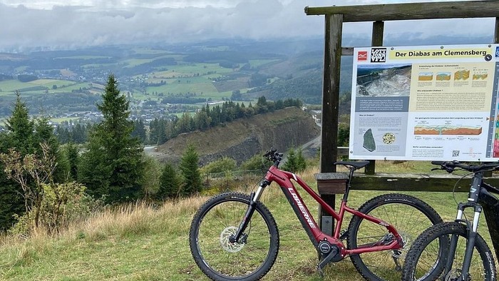 Fahrräder nahe einem Schild mit malerischer Aussicht auf Hügel und Bäume abgestellt