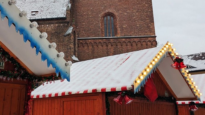 Weihnachtsmarktbude vor Kirche im Schnee.