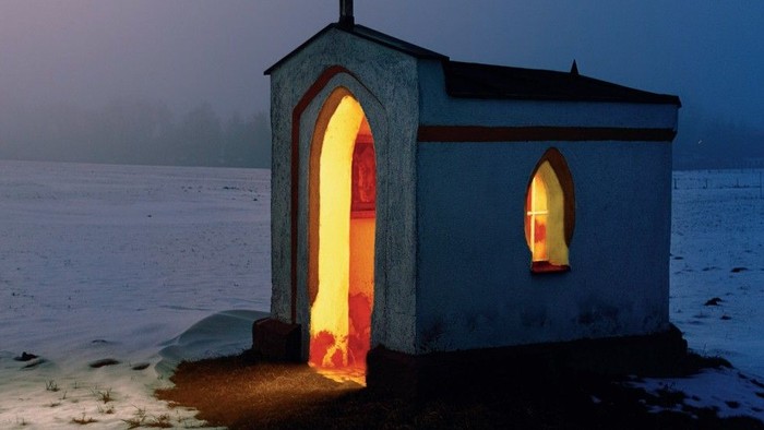 Kleine beleuchtete Kapelle in verschneiter Landschaft
