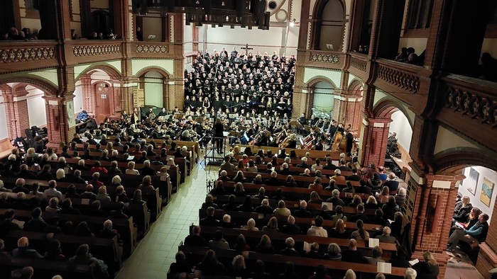 Ein Chor und ein Orchester geben in einer voll besetzten Kirche ein Konzert