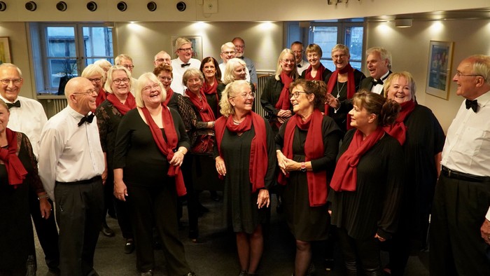 En gruppe af korister i formelle klæder samles til et billede