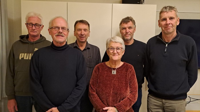 En gruppe af seks personer står sammen i et rum