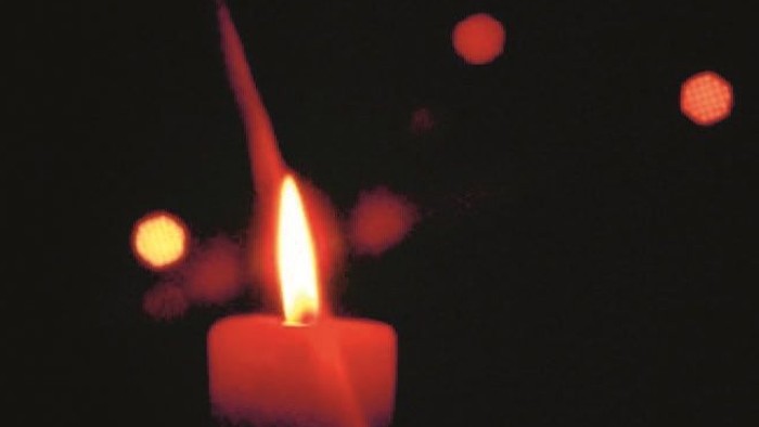 Eine rote Kerze leuchtet im dunklen.