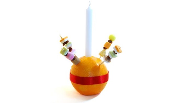 Orange with red stripe and candle, decorated with colorful skewers.