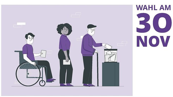 Drei Personen stehen an einem Informationsstand, eine im Rollstuhl.