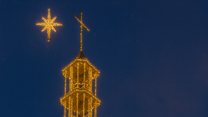 Silhouette eines Schneemanns vor hell erleuchteten Weihnachtsdekorationen.