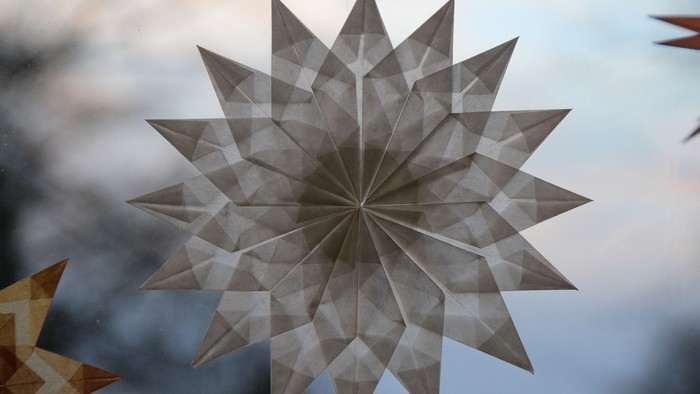 Aus weißem Pergamentpapier gefalteter Stern an einem Fenster