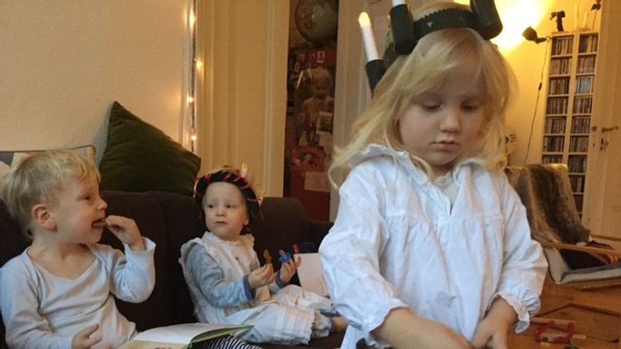 Drei Kinder spielen drinnen, eines mit einer Trommel.