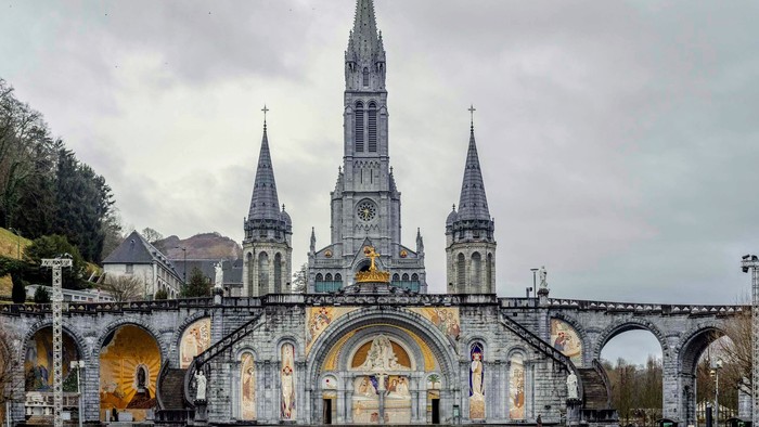 Große Basilika mit hohen Türmen und prunkvoller Fassade, umgeben von Bögen und Statuen.